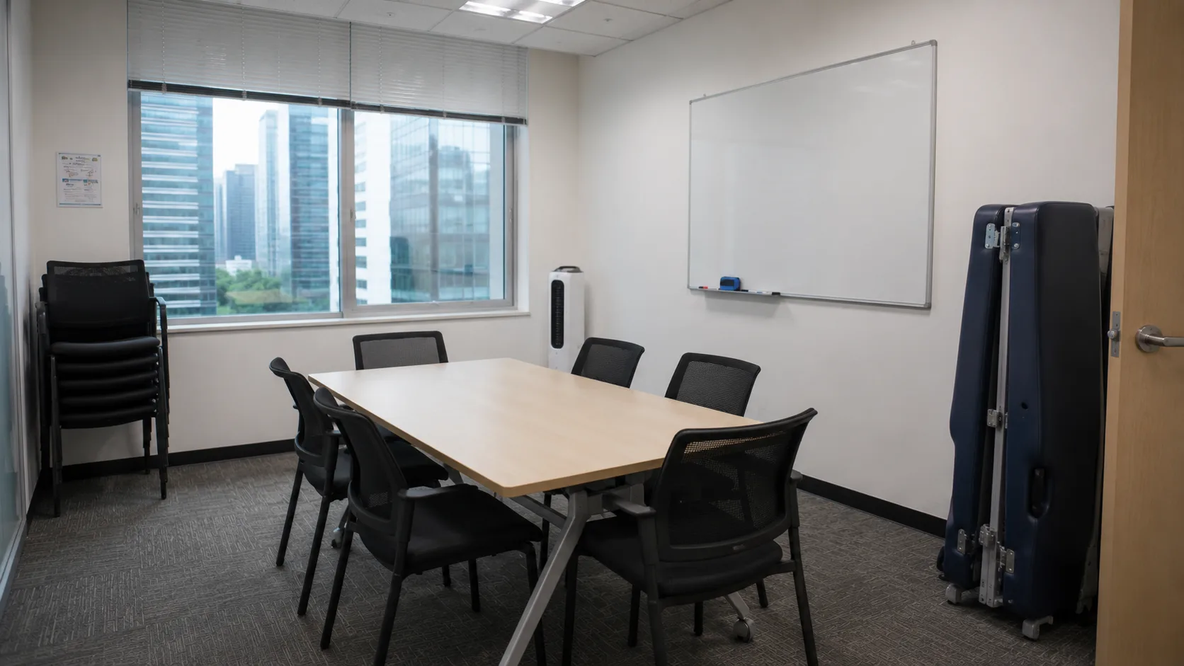 An empty office meeting room with a folded portable treatment table standing beside the door