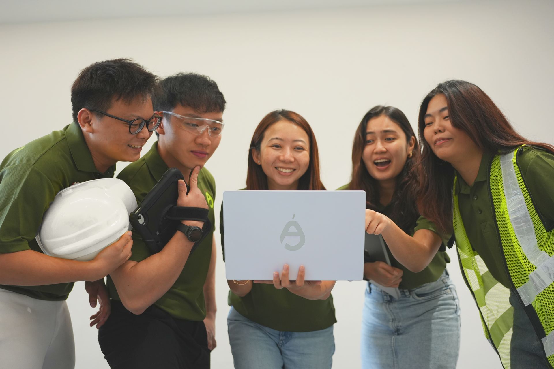 AnjouHealth team in workwear and safety gear collaborating around a laptop