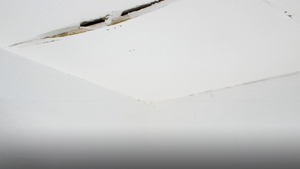 Close-up of a cracked ceiling panel, a visible warning sign of structural stress.