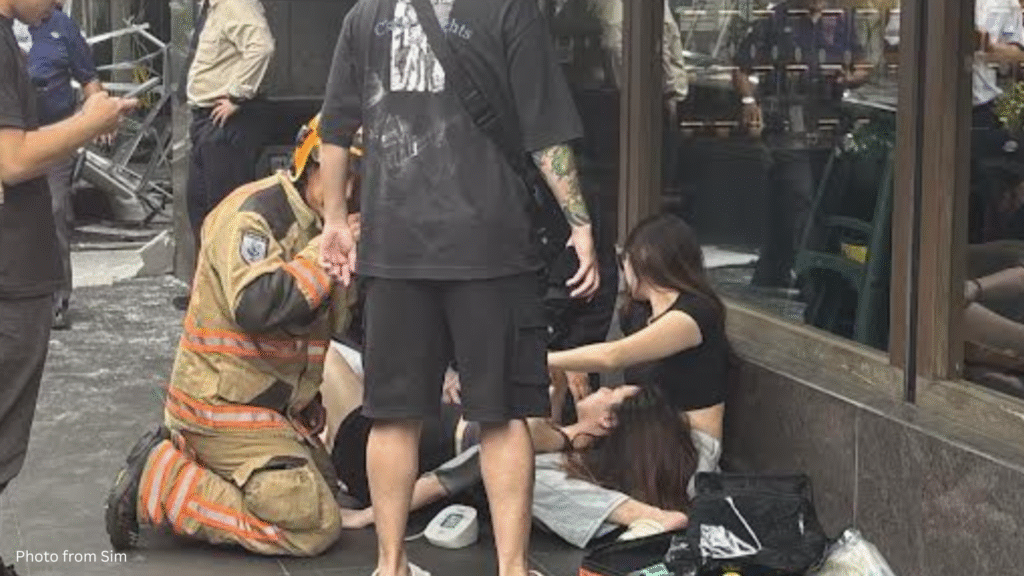 A woman lies on the ground surrounded by firefighters and bystanders following the ceiling collapse at Liat Towers.