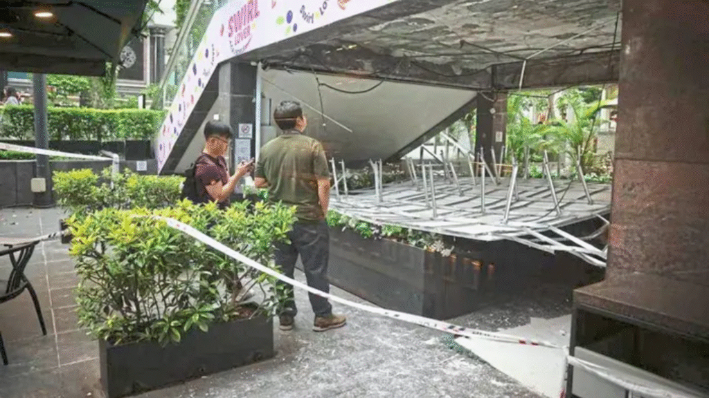 Scene of the Liat Towers ceiling collapse cordoned off with tape, showing the damaged structure and curious bystanders.