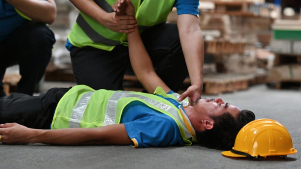 Safety personnel assisting injured worker on-site, highlighting the importance of safety compliance and quick response
