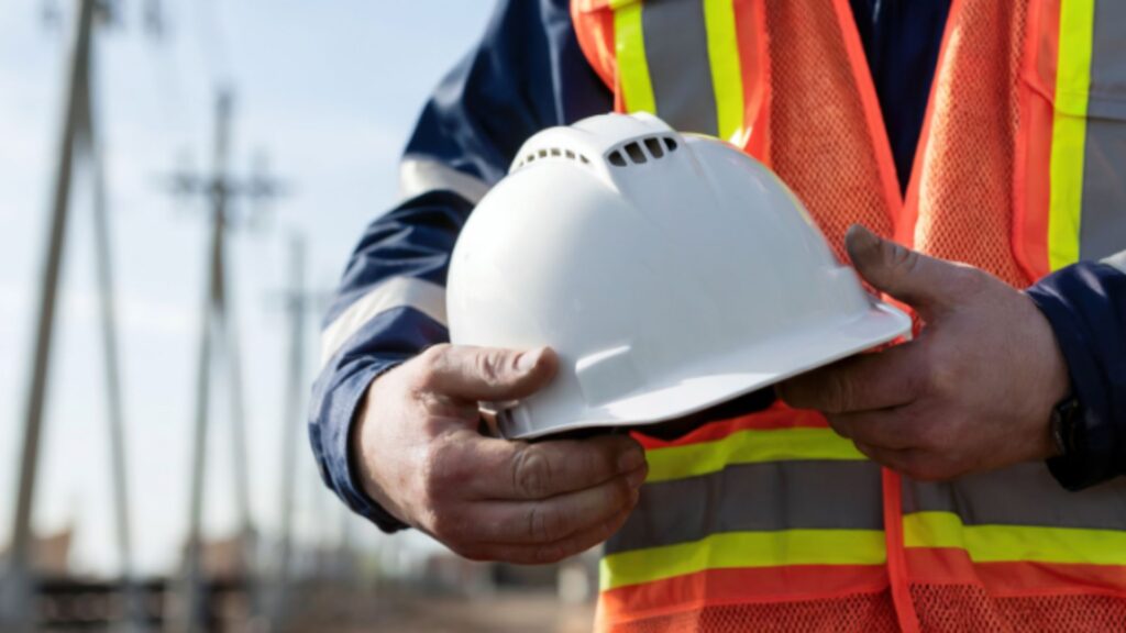 Construction worker holding safety helmet and wearing reflective vest, symbolising responsibility and safety culture