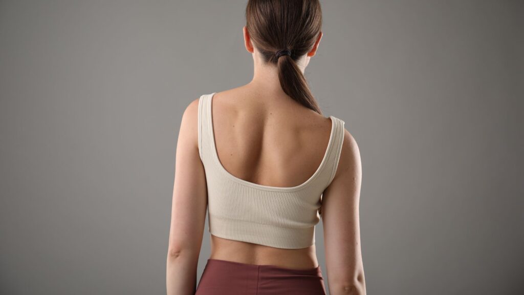 Rear view of a woman with visible spine alignment standing with neutral posture