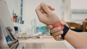 Office worker experiencing wrist pain from prolonged computer use, illustrating work-related musculoskeletal disorders in Singapore