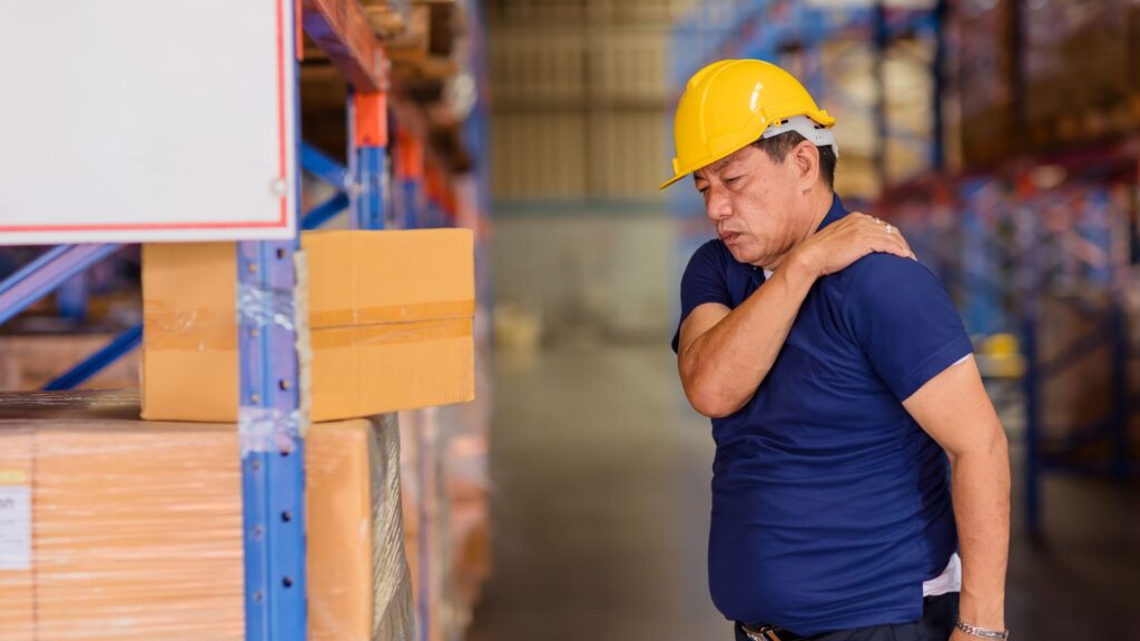 Worker experiencing shoulder pain from manual handling, a common workplace safety hazard in Singapore