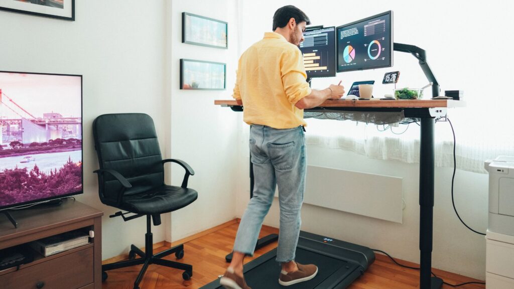 Employee standing on anti-fatigue mat at adjustable desk to reduce spinal compression and support SS 514 workplace ergonomics standards