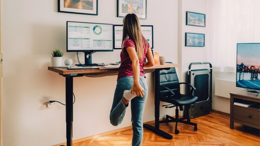 Workplace Ergonomics Singapore – employee using standing desk and stretching to maintain healthy posture and reduce back strain