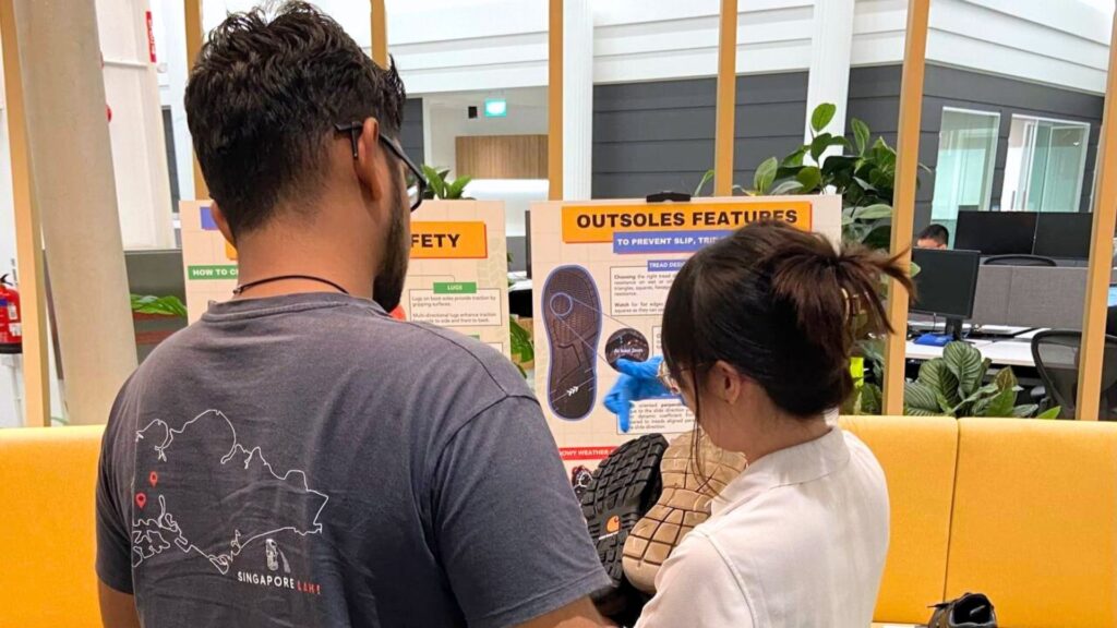 Workplace safety educator explaining shoe outsole features to employees during a slip and trip prevention awareness session
