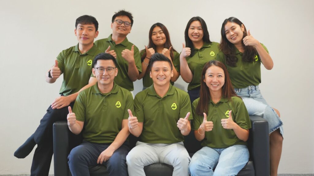 Corporate wellness team posing together in branded attire, showing thumbs up in a friendly group portrait