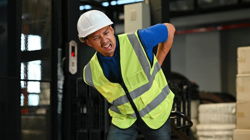 Warehouse worker experiencing lower back pain during manual work, a possible early sign of WMSD