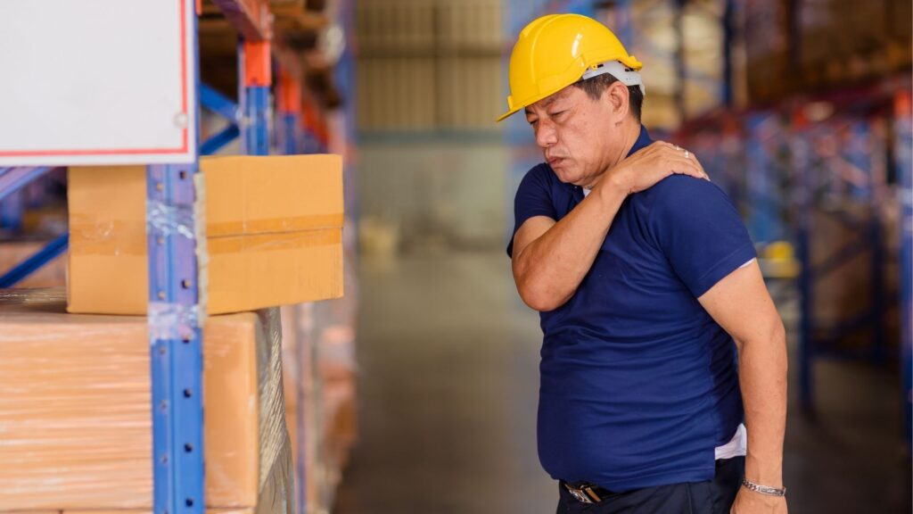 Manual worker with shoulder pain in warehouse environment showing an early sign of WMSD