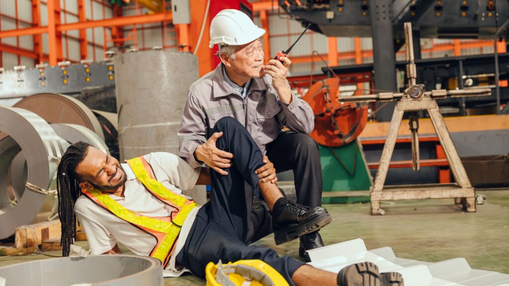 Worker injured in an industrial environment while a colleague calls for assistance, highlighting workplace safety risks and accident prevention in Singapore