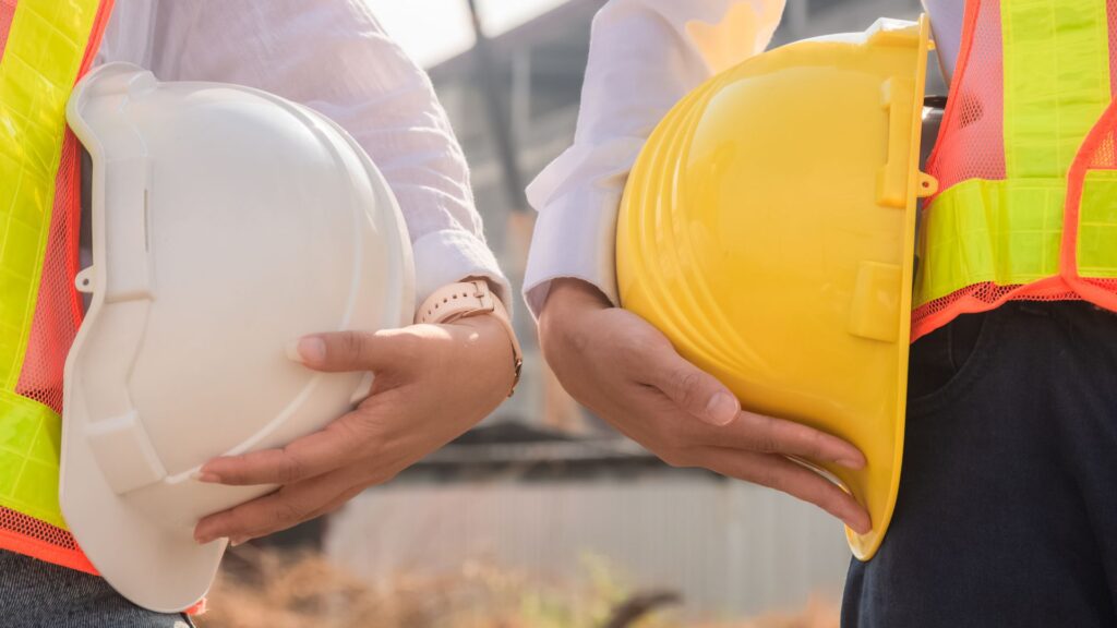 Supervisors holding safety helmets representing management commitment to occupational health and safety program Singapore implementation