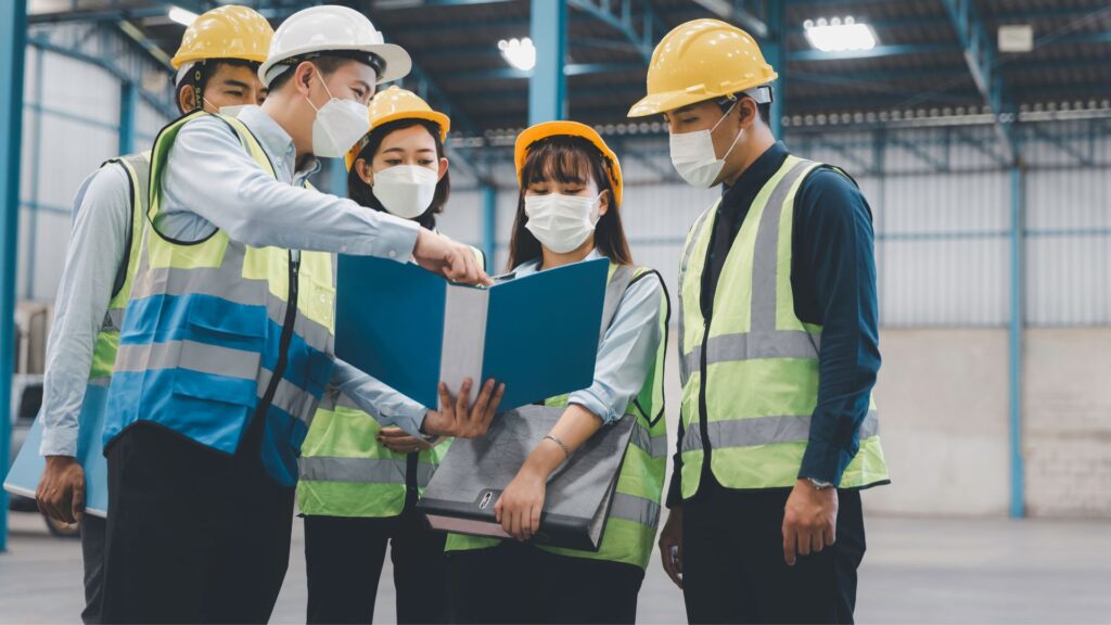 workers reviewing workplace safety risk assessment documents together singapore safety compliance responsibilities