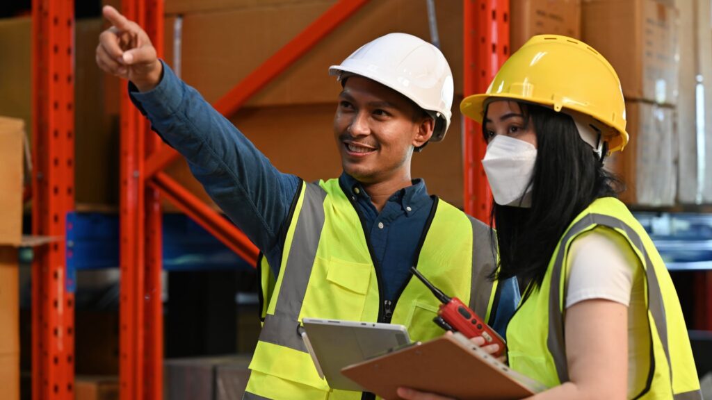 Supervisor guiding warehouse worker on safe handling procedures to prevent workplace injury in Singapore logistics environment