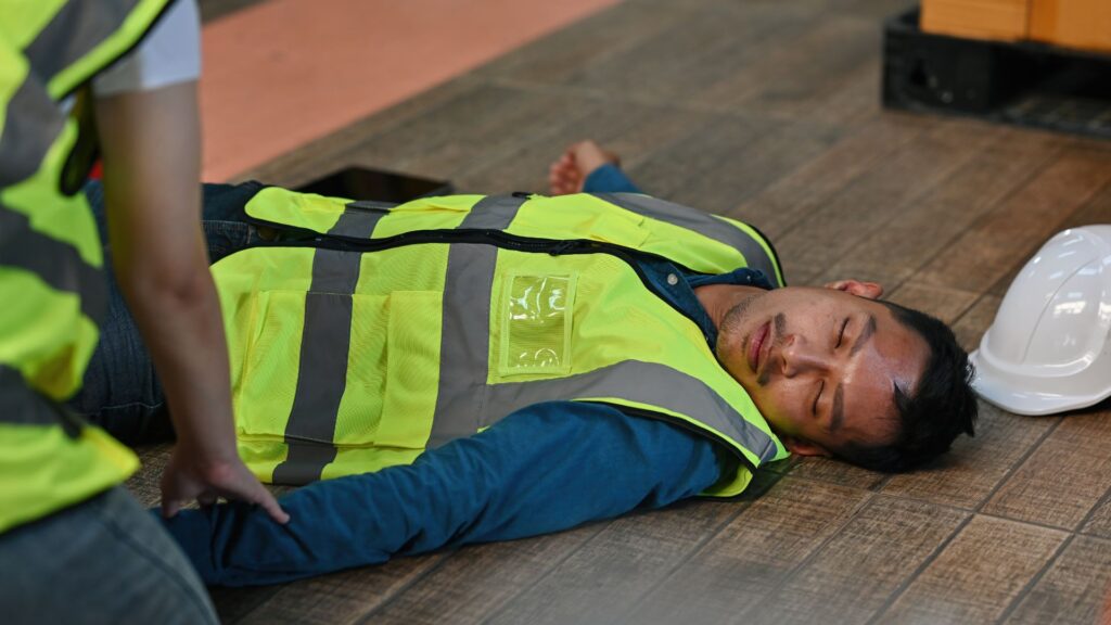 Injured warehouse worker lying on floor after workplace accident highlighting importance of workplace injury management and WICA support in Singapore