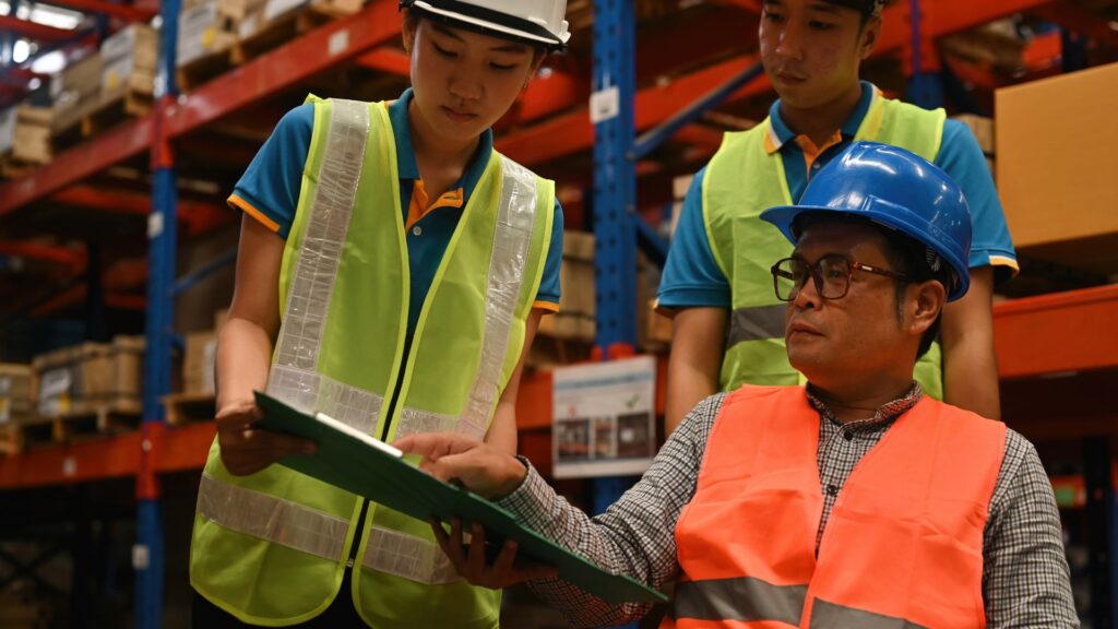 Supervisor reviewing safety documentation with warehouse staff to strengthen workplace injury prevention practices in Singapore
