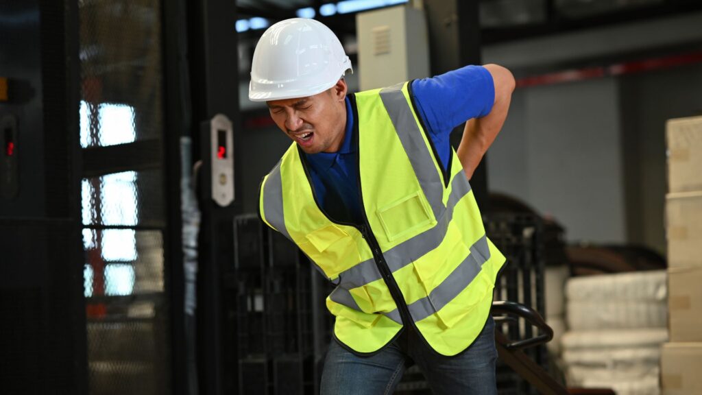 Warehouse worker experiencing lower back pain from manual handling injury requiring workplace physiotherapy treatment Singapore