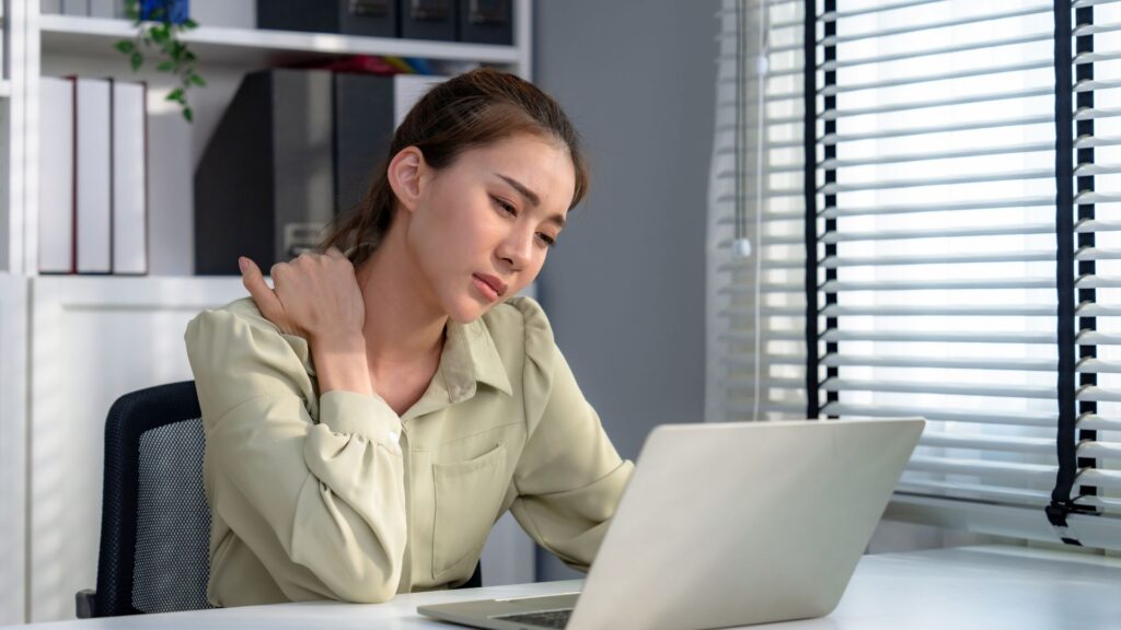 office worker experiencing neck and shoulder pain from poor workplace ergonomics Singapore